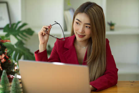 Happy asian young businesswoman or entrepreneur thinking up new marketing strategies for her company. daydreaming about achieving success.の写真素材