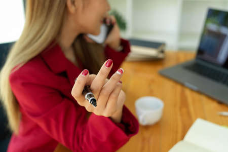 Close-up Confident business woman in red suit working or making a video call with business team via laptop computer at the office.の写真素材