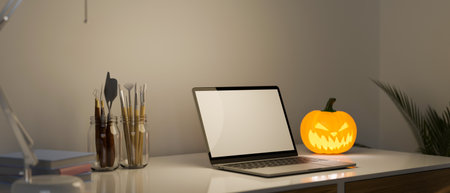 Laptop white screen mockup with painting tools, halloween pumpkin lamp and accessories on the desk. artist's desk concept. 3d rendering, 3d illustrationの写真素材