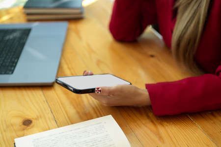 Close-up image of business woman in red suit looking at smartphone screen, hand holding mobile phone. phone blank screen.の写真素材