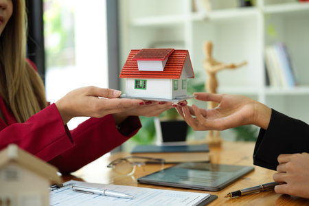 Close-up image of business women or real estate broker holding house model together. property investment concept.の写真素材