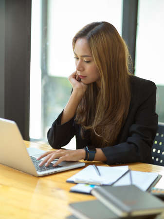 Female in strategy team focused on her works at the office, using computer notebook to analyse data.の写真素材