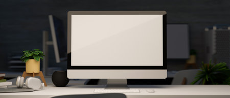 Modern dark office studio with desktop computer blank screen mockup on table. Workspace at night...