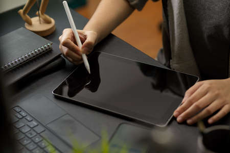 Cropped image of a female using stylus pen to draws on digital tablet computer on modern office deskの写真素材