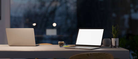 Modern co-working space in office at night with two laptop computer mockup on a table over large window. 3d rendering, 3d illustrationの写真素材