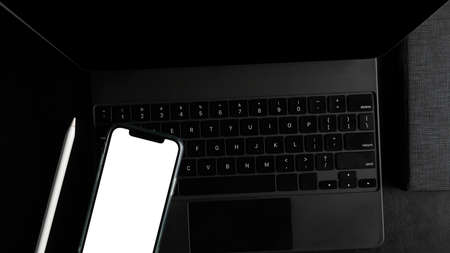 Top view, flay, Smartphone blank screen mockup on modern digital tablet computer in dark workspace.の写真素材