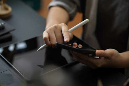 Closeup, a female freelancer using modern smartphone at her working desk. Woman holding mobile phoneの写真素材