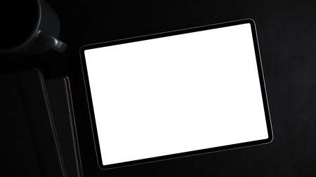 Top view, flat lay image of a tablet computer white screen mockup on modern black workspace.の写真素材