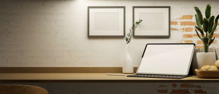 Close-up, A simple working space on wooden table with copy space, tablet computer mockup, blank frame on brick wall and decor. 3d rendering, 3d illustrationの写真素材