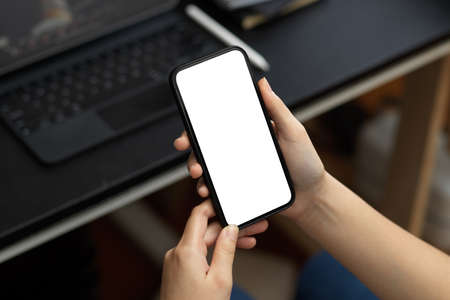 A female employee relaxed on her smartphone at her desk. A young woman chatting with her friends on mobile phone.の写真素材