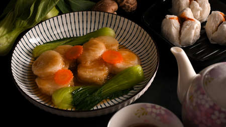 Homemade braise bean curd with special sauce and vegetables in a porcelain plate, Chinese buns and a tea set.の写真素材