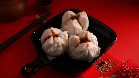 Steamed red minced pork buns on a plate, chopsticks and a new year card on a table. Chinese appetiser concept. Translation: Fu meaning good fortuneの写真素材
