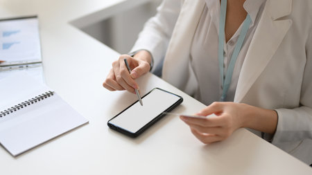A business woman or female entrepreneur using a smartphone with stylus pen at her desk. smartphone blank screen mockup.の写真素材
