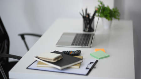 Side view of a workspace with portable laptop computer mockup and office supplies on white table.の写真素材