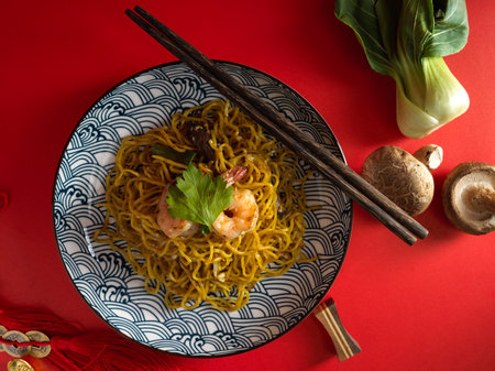 A homemade delicious chow mein or Chinese stir fried with shrimp on a porcelain plate over red background. Chinese food concept.の写真素材