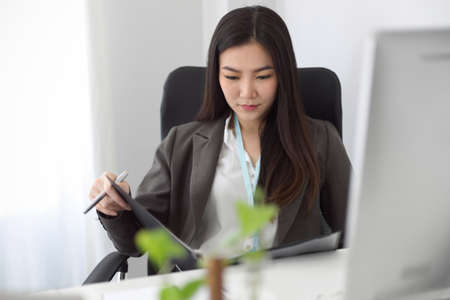 A business woman or female accountant looking at the financial report on a binder file at her modern office space.の写真素材