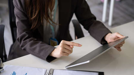 Close-up image of a business woman holding a digital tablet computer, using touchpad to communicate with her coworker.の写真素材