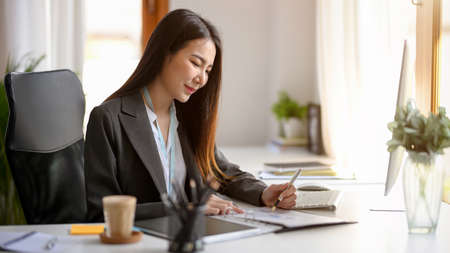A business female entrepreneur is making a plan for her new product at her desk. an Asian businesswoman is working in the office.の写真素材