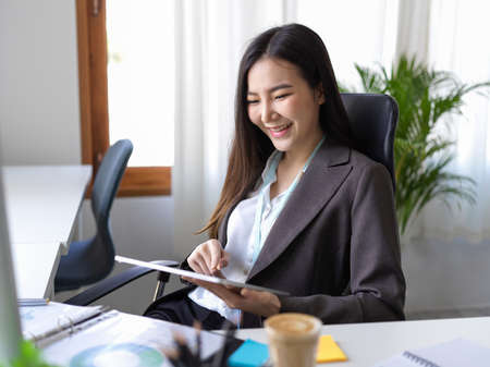 Businesswoman using digital tablet touchpad computer at her desk. Female manager using tablet to chat with her friends.の写真素材
