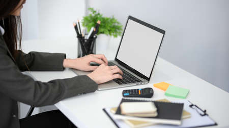 Close-up image of a female accountant working her laptop computer at her office desk. laptop blank screen mockup.の写真素材