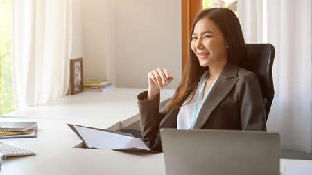 Female executive manager sitting in the modern office. Asian business woman reading the documents at her desk.の写真素材