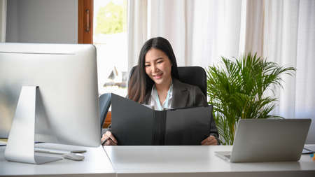 Executive female manager reading the business contract document on binder folder at her office desk.の写真素材