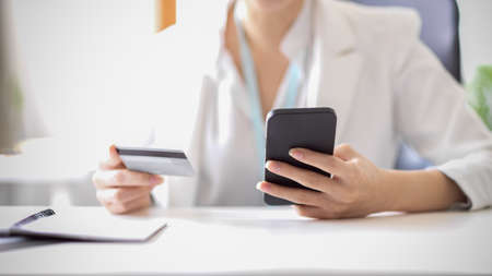 Cropped image of a businesswoman makes a purchase on the internet and pay on mobile banking application. Woman with smartphone and credit card.の写真素材