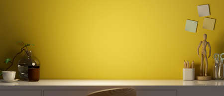 Creative workspace with stationery, decor and copy space for product display over yellow background....