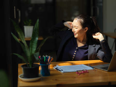 Relaxed business woman working on laptop computer at her office desk. Happy and cheerful businesswoman.の写真素材