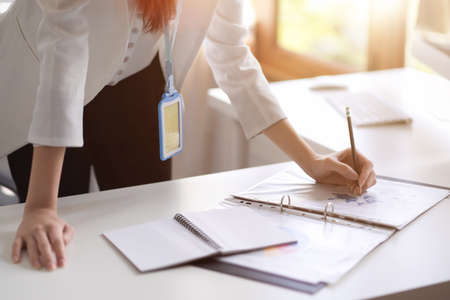Business woman or female manager leaning on table and signing a business contract document in her office. cropped imageの写真素材