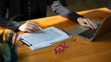 Cropped shot of a business woman checking her stock data report paperwork at her office desk.の写真素材