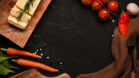 Top view, overhead, A copy space on black background with vegetables. Butter, carrots, tomatoes, mushroom and chilli.の写真素材