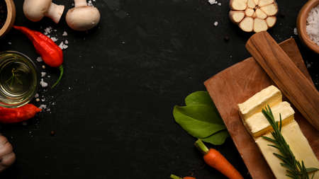 Copy space on black background surrounded with vegetables and butter. carrots, tomatoes, garlic, mushroom and chilli. top viewの写真素材
