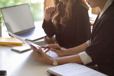 Cropped image of two businesswomen looking at tablet screen and planning a new business model together in the modern office room.の写真素材