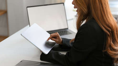 Close-up of an Asian successful business woman using digital tablet touchpad at her office desk.の写真素材