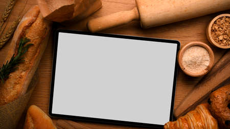 Digital tablet touchpad white screen mockup for montage your graphic pastry recipe with bread background. top view, flat layの写真素材
