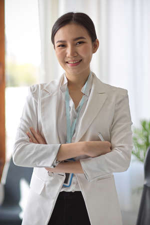 Portrait of a beautiful confident Asian businesswoman crossed arms or folded arms while standing in modern office workplace.の写真素材