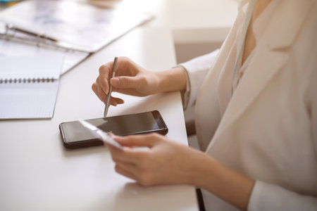 Cropped image of a female using stylus pen with a smartphone and holding a credit card. Mobile banking conceptの写真素材