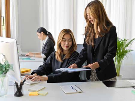 A female marketing officer asking her colleague to explain the work assignment in the modern office.の写真素材