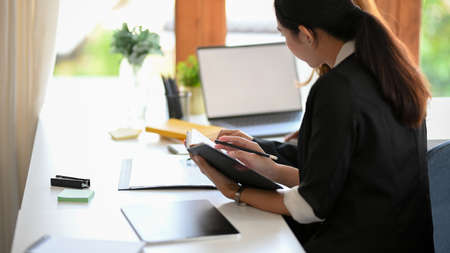 Asian female secretary working at her office desk. Businesswoman sitting at her workplace.の写真素材
