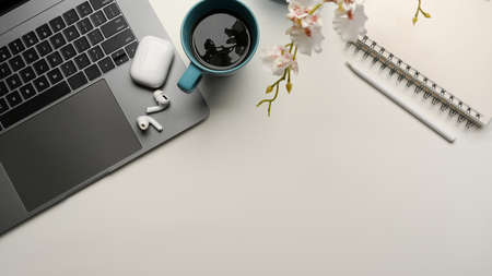 Modern office workspace with laptop computer, earbuds, decor and copy space on white table background. top viewの写真素材