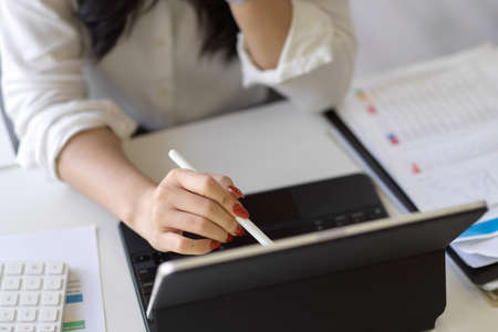 Close-up image of a female using stylus pen with portable tablet computer at her office desk.