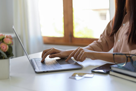 Cropped image of a female using laptop computer. Female college student doing her online assignment on notebook computer.の写真素材