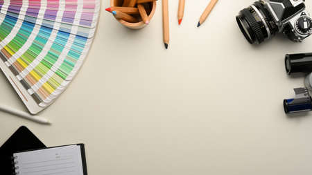 Graphic designer or photographer workspace with colour palette samples, stationery, camera and copy...