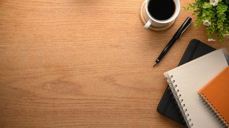 Wooden workspace with notebooks, coffee cup, and copy space for product display. top viewの写真素材