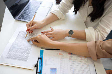 Close-up image of an accountant analysing financial data in spreadsheet paperwork at office desk.の写真素材