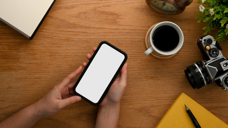 Close-up, top view image of a female blogger using her smartphone to upload her online content. smartphone white screen mockup.の写真素材