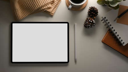 Tablet touchpad computer white screen mockup on a table with cozy and warm decorations stuff. Feminine worktable conceptの写真素材