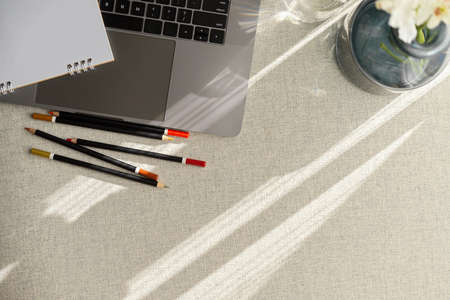Simple flat lay office desk with laptop computer, pencils, flower vase and copy space on table.の写真素材
