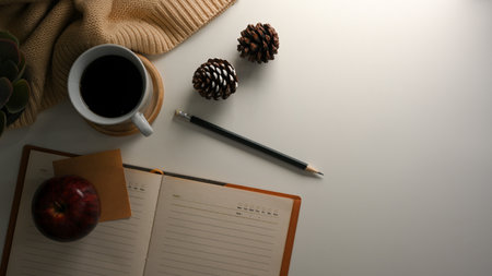 Cozy workspace with coffee cup, sweater, diary book, stuff and copy space on white background. top viewの写真素材